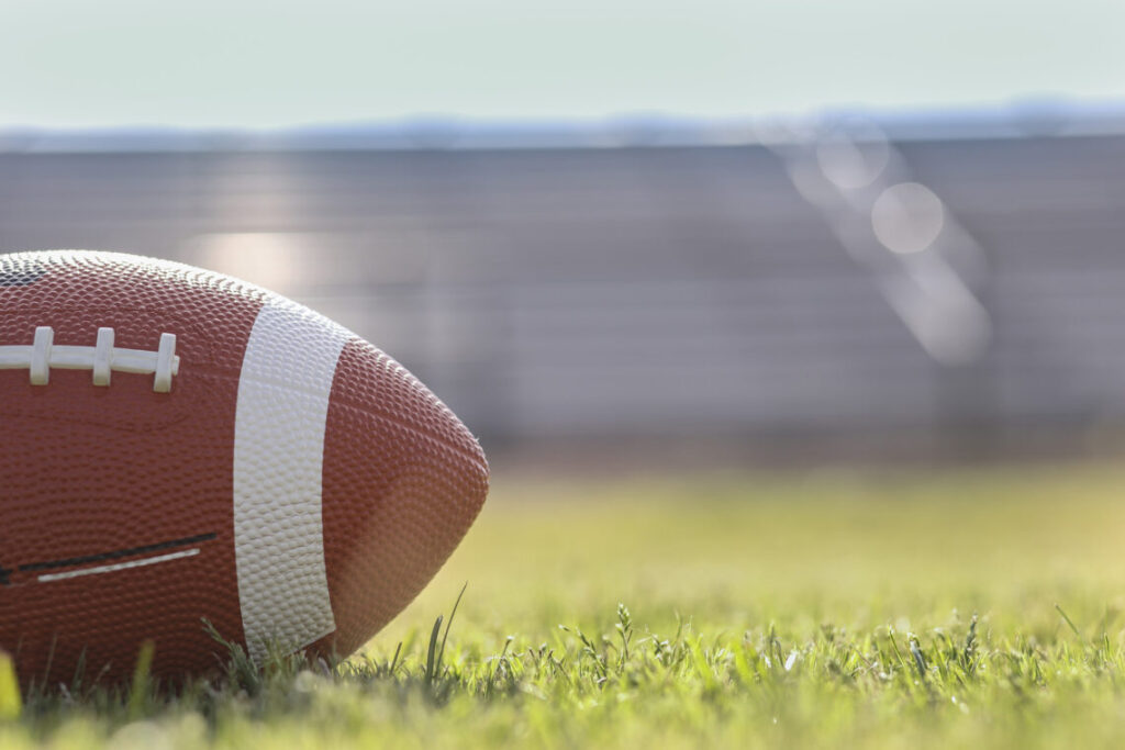 American football on stadium field at school campus.